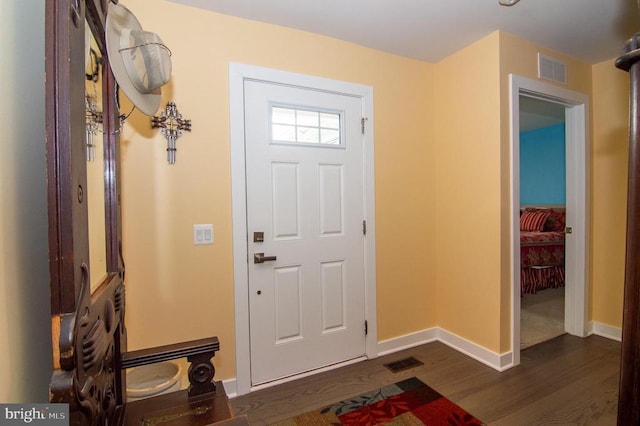 foyer entrance featuring baseboards, visible vents, and dark wood-type flooring