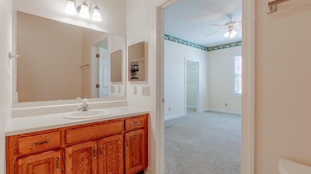 bathroom featuring a textured ceiling, toilet, ceiling fan with notable chandelier, vanity, and baseboards