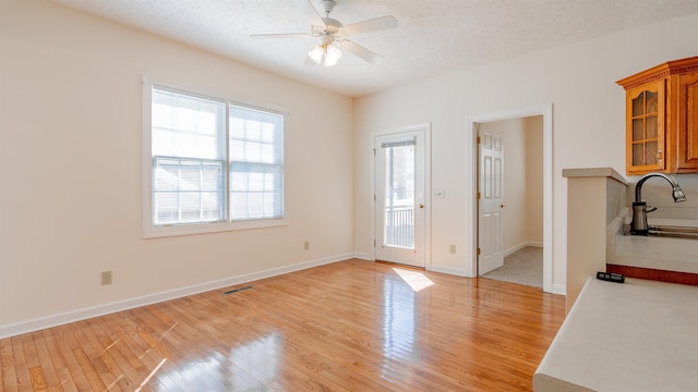 interior space featuring a ceiling fan, light wood-type flooring, and a textured ceiling