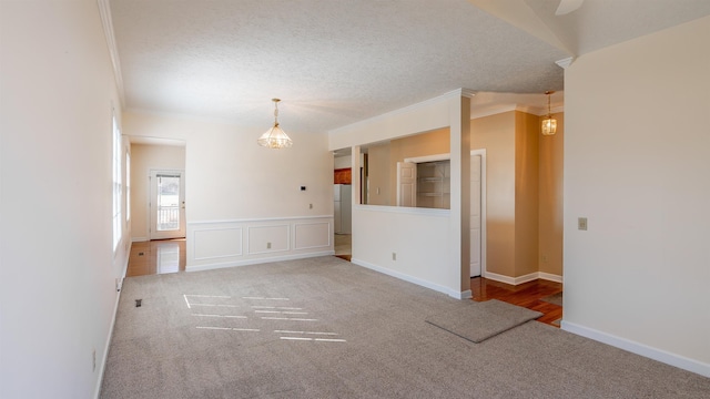 spare room featuring a textured ceiling, ornamental molding, carpet, and baseboards