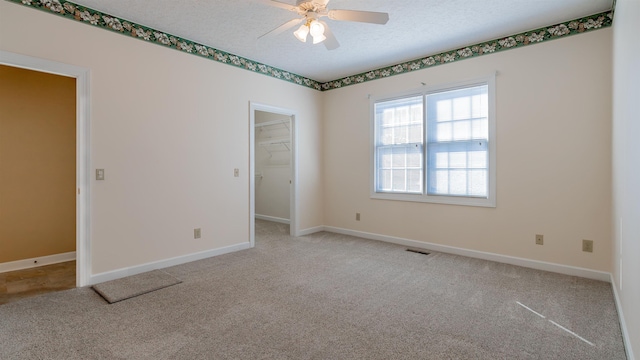 spare room featuring light carpet, visible vents, and a textured ceiling