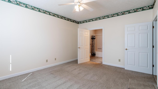 unfurnished bedroom featuring light colored carpet, ceiling fan, a textured ceiling, and baseboards