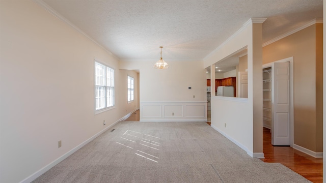 spare room featuring a textured ceiling, ornamental molding, and baseboards