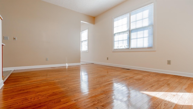 empty room featuring light wood-style floors, visible vents, and baseboards