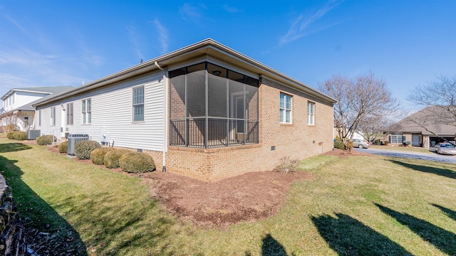 view of side of home with a sunroom, crawl space, a lawn, and central AC unit