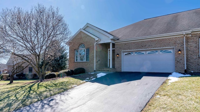 ranch-style home featuring brick siding, aphalt driveway, roof with shingles, an attached garage, and a front yard