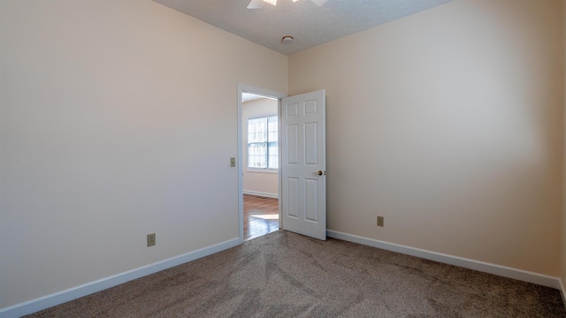 empty room featuring carpet and baseboards