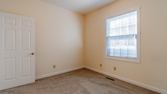 spare room featuring light carpet, visible vents, and baseboards