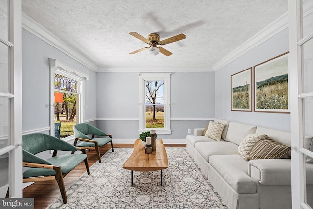 living room featuring a healthy amount of sunlight, crown molding, and wood finished floors