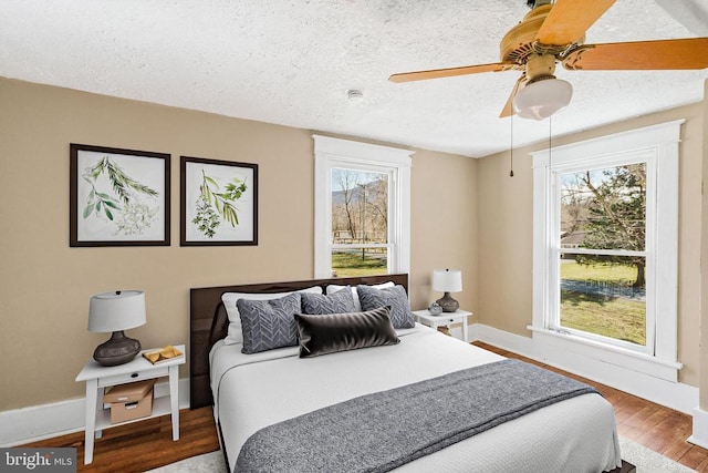 bedroom featuring a textured ceiling, a ceiling fan, baseboards, and wood finished floors