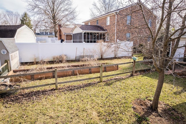 view of yard featuring a vegetable garden, fence, and a sunroom