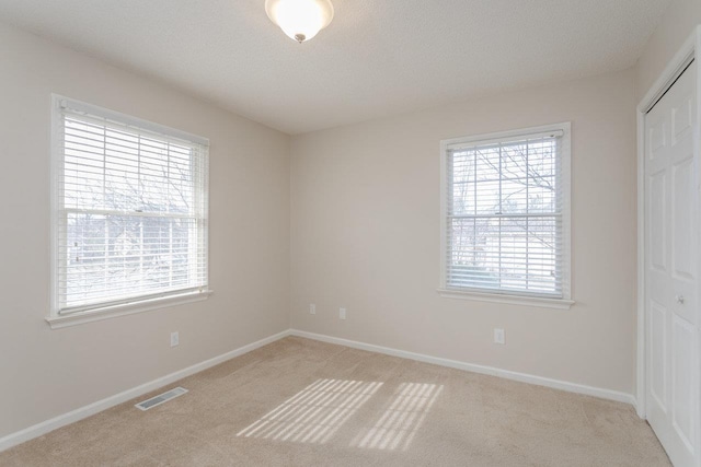 unfurnished bedroom with carpet, visible vents, a closet, and baseboards