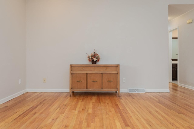 unfurnished room with light wood-type flooring, visible vents, and baseboards