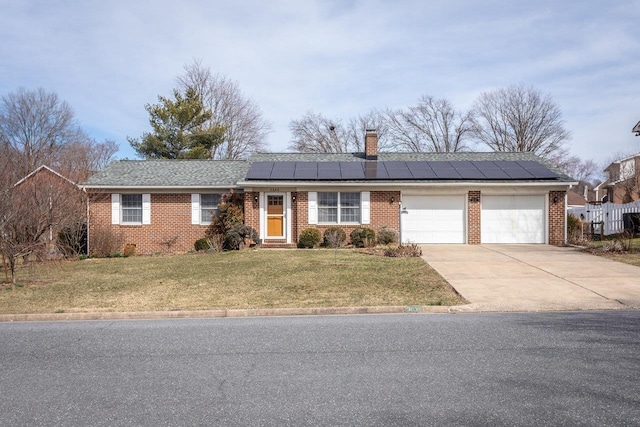 ranch-style home with solar panels, a front lawn, a chimney, driveway, and an attached garage