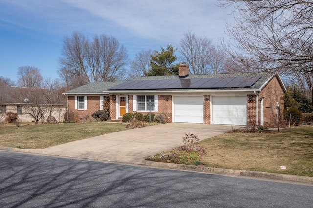 ranch-style home featuring driveway, a front lawn, roof mounted solar panels, brick siding, and a chimney