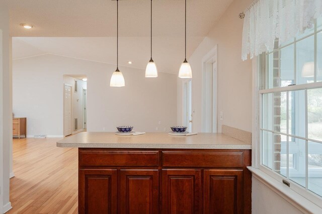 kitchen featuring a wealth of natural light, light wood-style flooring, pendant lighting, and light countertops