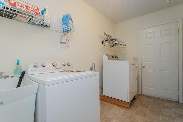 clothes washing area with washer and dryer, a textured ceiling, laundry area, and a sink