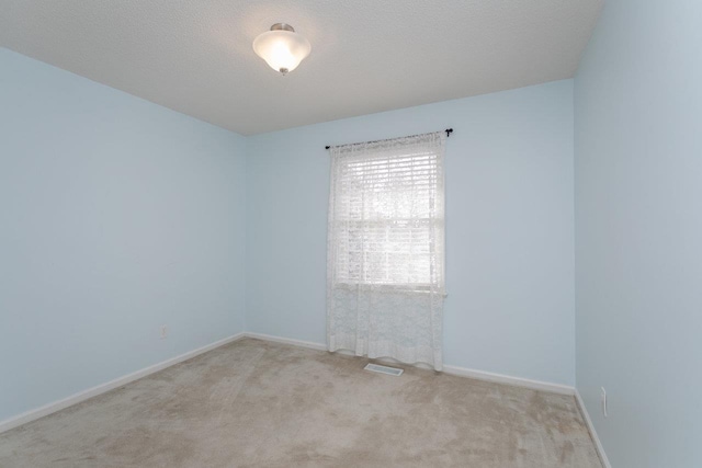 carpeted spare room with baseboards and a textured ceiling