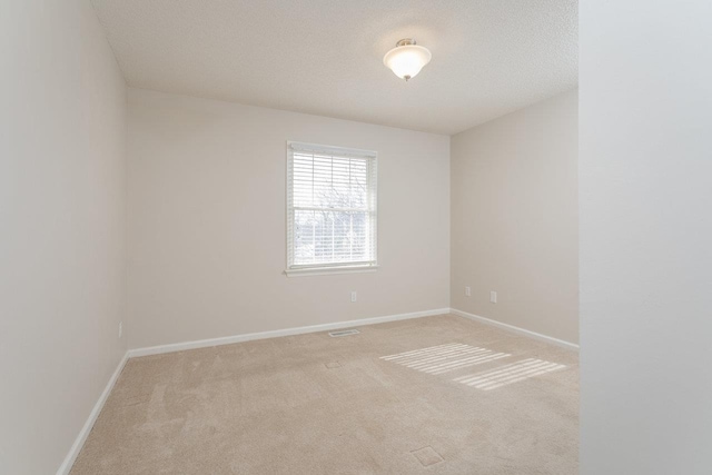 empty room featuring a textured ceiling, visible vents, baseboards, and light carpet