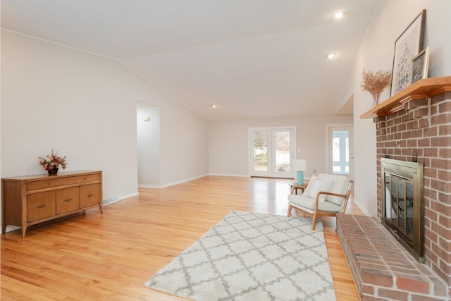 sitting room featuring light wood-type flooring, recessed lighting, baseboards, a brick fireplace, and vaulted ceiling