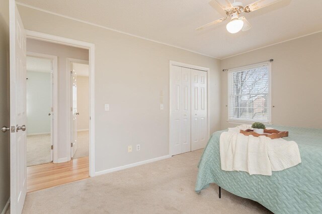 carpeted bedroom featuring a closet, baseboards, and ceiling fan