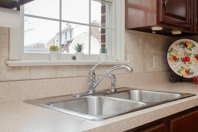 kitchen featuring dark brown cabinets, light countertops, and a sink