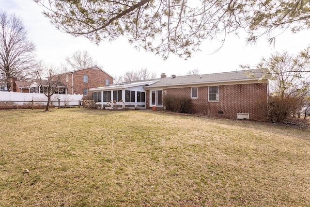 back of house featuring brick siding, fence, a yard, a sunroom, and crawl space