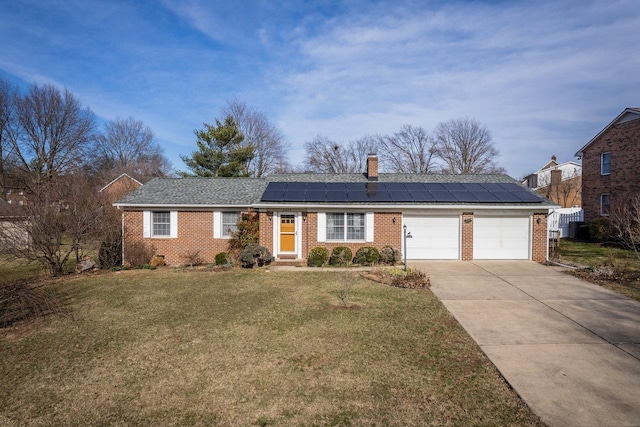 ranch-style home featuring a front yard, concrete driveway, a garage, brick siding, and roof mounted solar panels