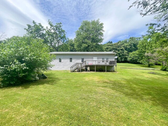 back of property featuring a deck and a lawn