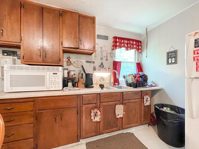 kitchen with light tile patterned flooring, sink, and white appliances