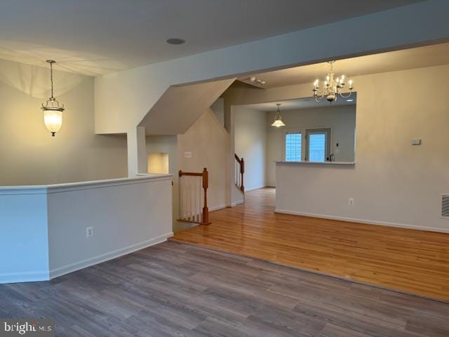 spare room featuring visible vents, wood finished floors, baseboards, and a chandelier