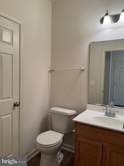 half bath with vanity, toilet, and baseboards