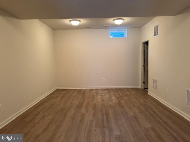 empty room with dark wood finished floors, baseboards, and visible vents