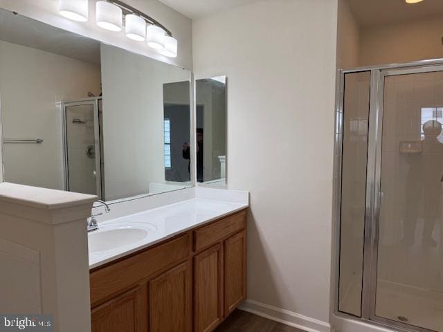 full bath featuring a stall shower, vanity, and baseboards