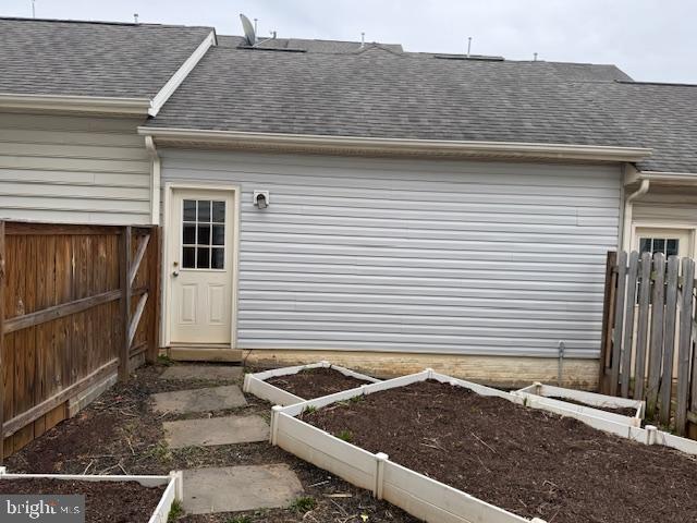 property entrance with fence and a shingled roof