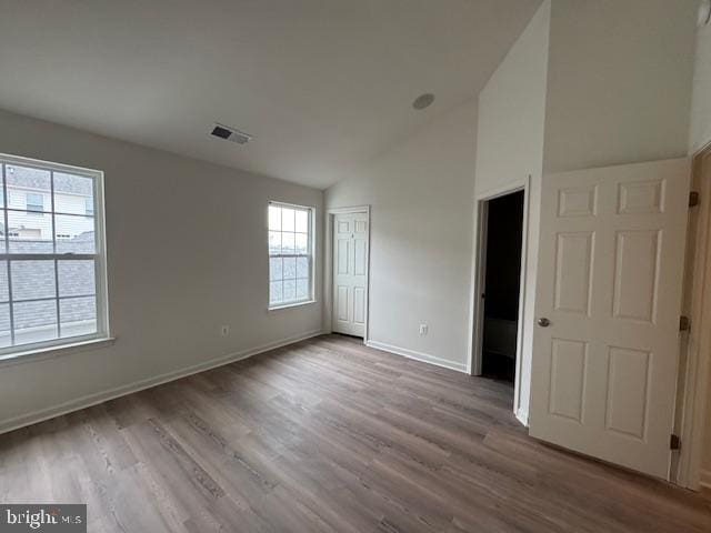 unfurnished bedroom featuring wood finished floors, baseboards, visible vents, high vaulted ceiling, and a closet