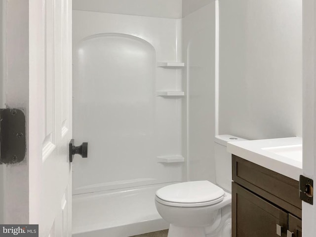 bathroom featuring a shower, vanity, and toilet