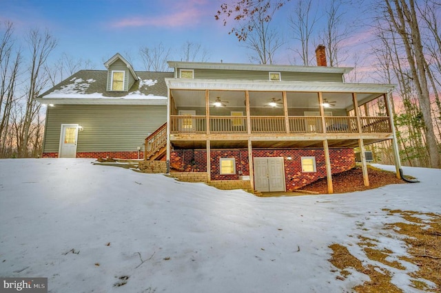 snow covered house with a sunroom and ceiling fan