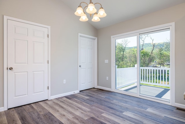 interior space with visible vents, wood finished floors, baseboards, a chandelier, and vaulted ceiling