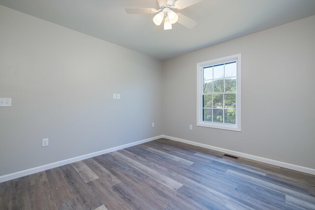 unfurnished room with a ceiling fan, baseboards, visible vents, and dark wood-style floors