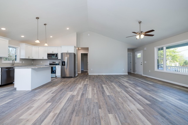 kitchen featuring open floor plan, a center island, white cabinets, a ceiling fan, and appliances with stainless steel finishes