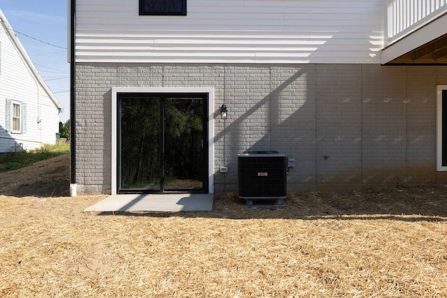 view of exterior entry featuring brick siding and cooling unit