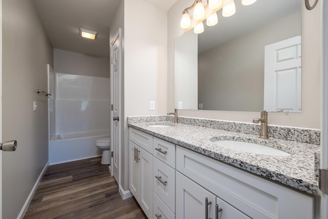 full bath featuring double vanity, toilet, a sink, and wood finished floors