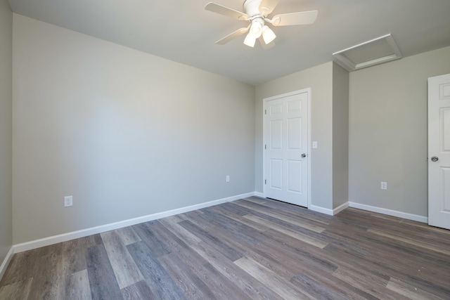 unfurnished bedroom with baseboards, attic access, and dark wood-style flooring