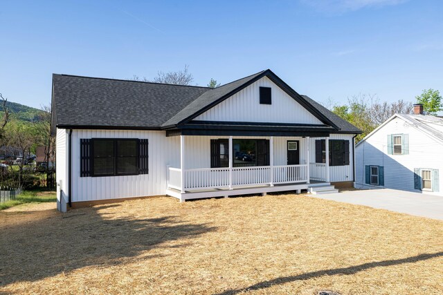modern inspired farmhouse with a shingled roof and a porch