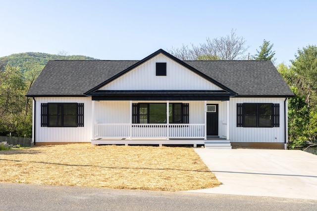 modern farmhouse featuring a porch, driveway, and a shingled roof