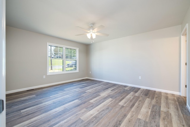 unfurnished room featuring baseboards, a ceiling fan, wood finished floors, and visible vents