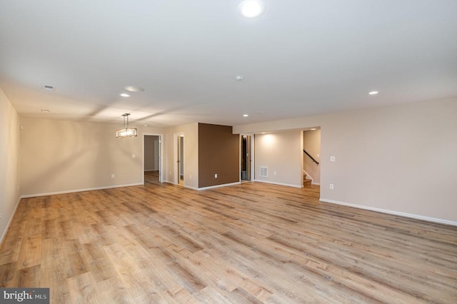 empty room with stairway, recessed lighting, light wood-style flooring, and baseboards