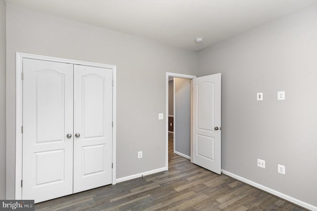 unfurnished bedroom with wood finished floors, baseboards, and a closet