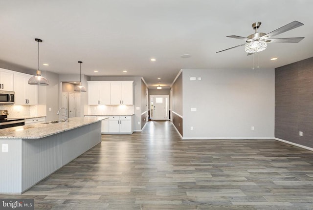 kitchen with backsplash, stainless steel appliances, a ceiling fan, and a sink